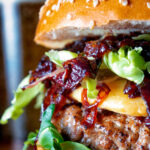 Clsoe up profile of a veal burger with port onions, gouda cheese and crispy parma ham.