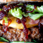 Close up veal burger with port onions, gouda cheese and crispy parma ham.