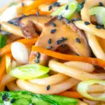 Close up Vegan yaki udon noodles with shiitake mushrooms, carrots and pak choi featuring a title overlay.