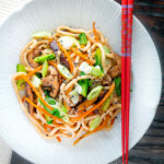 Overhead vegan yaki udon noodles with shiitake mushrooms, carrots and pak choi featuring a title overlay.