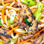 Overhead close up yaki udon noodles with shiitake mushrooms, carrots and pak choi.