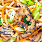 Overhead close up yaki udon noodles with shiitake mushrooms, carrots and pak choi featuring a title overlay.