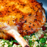 Clos up rose harissa glazed roasted pork chops with bulgur wheat salad.