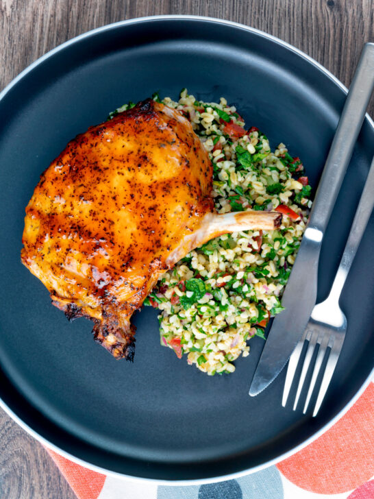 Overhead rose harissa glazed roasted pork chops with bulgur wheat salad.