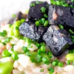 Close up black pudding risotto with bacon, broad beans and garden peas.