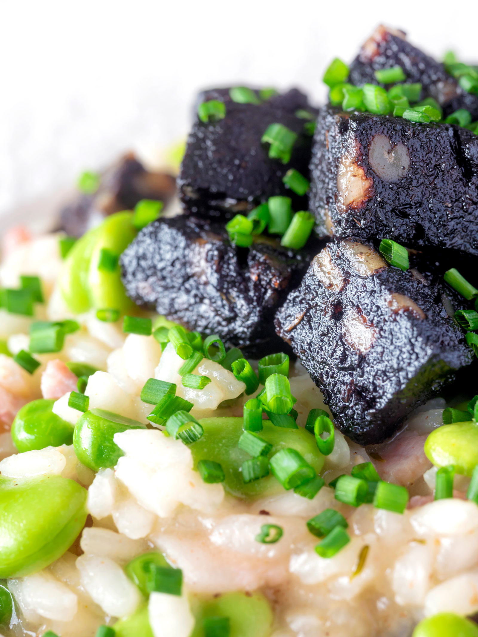 Close up black pudding risotto with bacon, broad beans and garden peas.