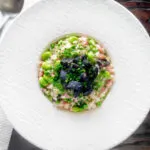 Overhead black pudding risotto with bacon, broad beans and garden peas.