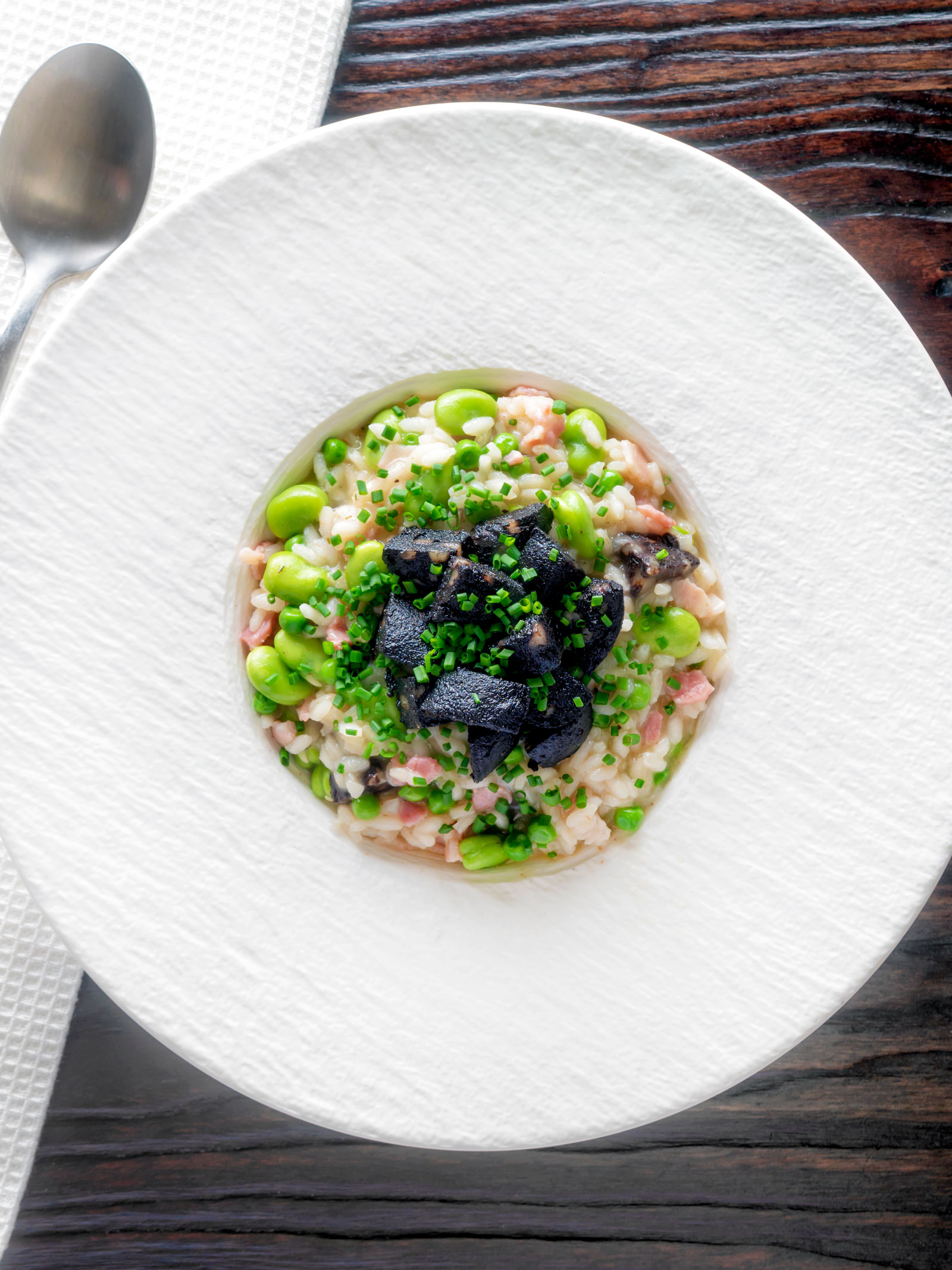 Overhead black pudding risotto with bacon, broad beans and garden peas.