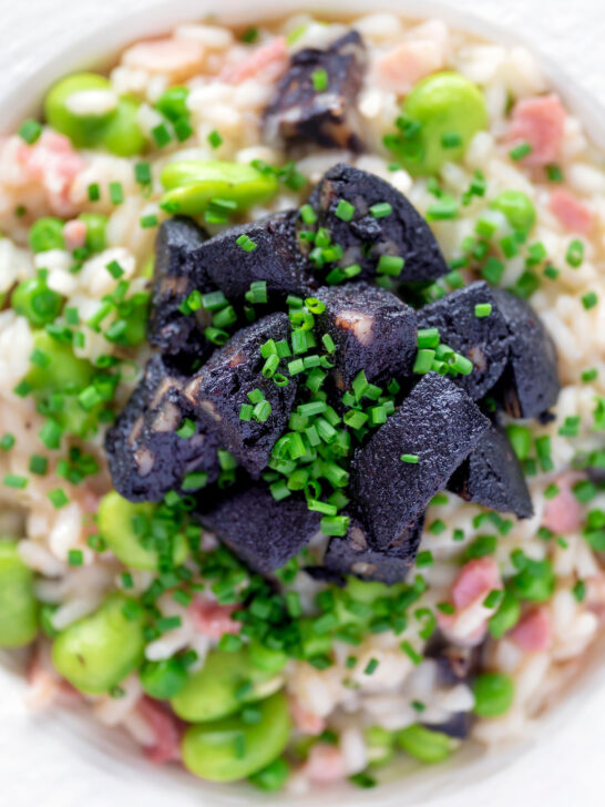 Overhead close up black pudding risotto with bacon, broad beans and garden peas.