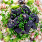 Overhead close up black pudding risotto with bacon, broad beans and garden peas featuring a title overlay.