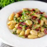 Creamy blue cheese gnocchi with stilton, asparagus and bacon featuring a title overlay.