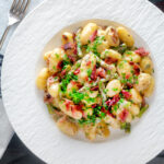 Overhead creamy blue cheese gnocchi with stilton, asparagus and bacon.