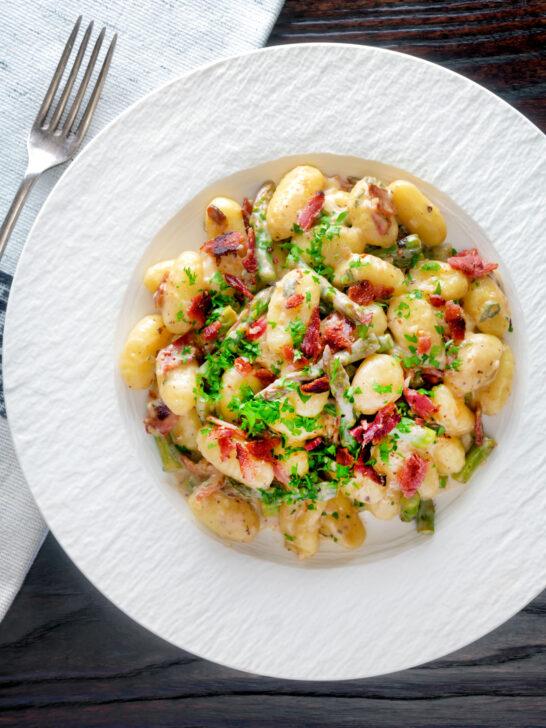 Overhead creamy blue cheese gnocchi with stilton, asparagus and bacon.