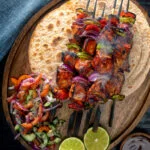 Overhead chicken shashlik kebab sticks with chapatis and kachumber salad.