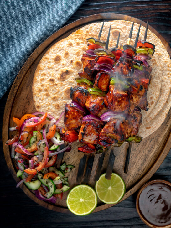 Overhead chicken shashlik kebab sticks with chapatis and kachumber salad.