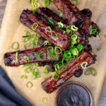Overhead Chinese takeaway style spare ribs with a dipping sauce.