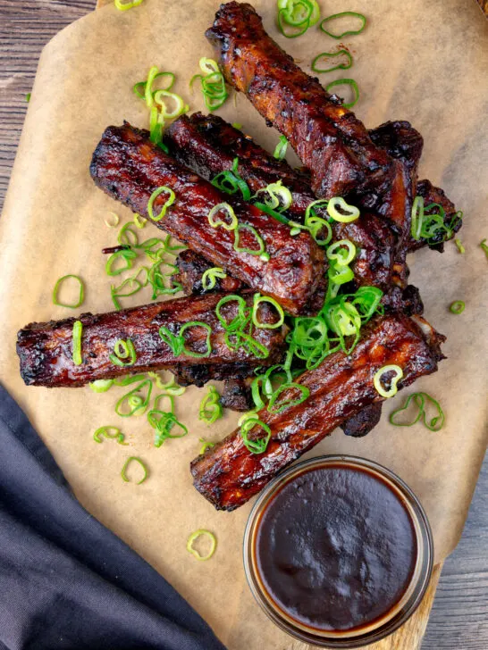 Overhead Chinese takeaway style spare ribs with a dipping sauce.