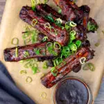 Overhead Chinese takeaway style spare ribs with a dipping sauce featuring a title overlay.