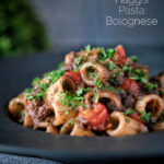 Haggis pasta bolognese with mezzi rigatoni in red wine sauce with cherry tomatoes featuring a title overlay.