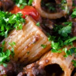 Close up haggis pasta bolognese with mezzi rigatoni in red wine sauce with cherry tomatoes.