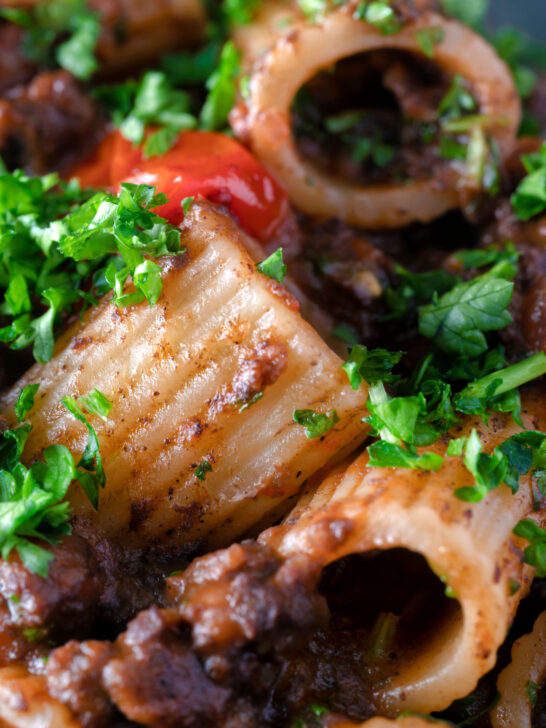 Close up haggis pasta bolognese with mezzi rigatoni in red wine sauce with cherry tomatoes.