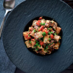 Overhead haggis pasta bolognese with mezzi rigatoni in red wine sauce with cherry tomatoes.
