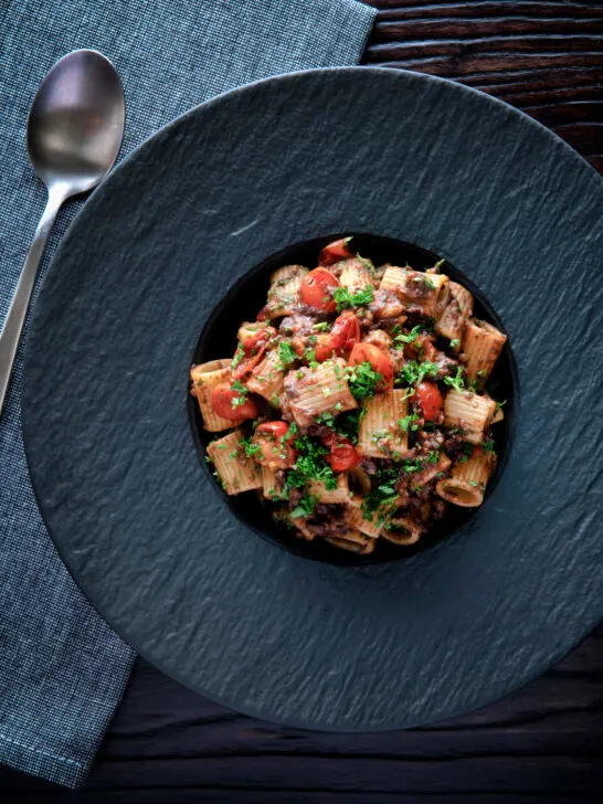 Overhead haggis pasta bolognese with mezzi rigatoni in red wine sauce with cherry tomatoes.