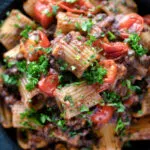 Overhead close up haggis pasta bolognese with mezzi rigatoni with cherry tomatoes.