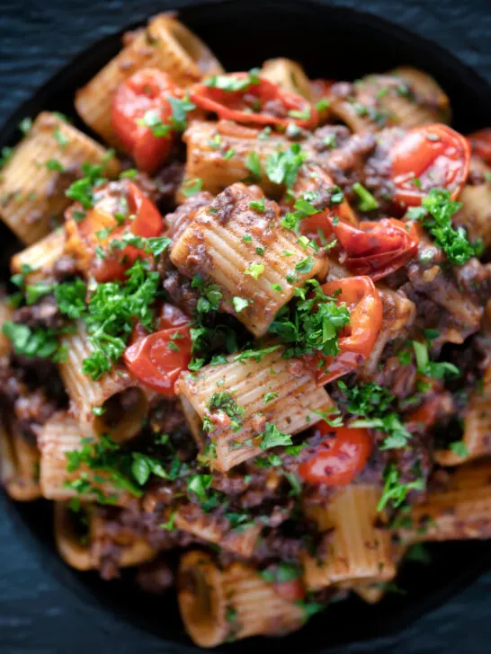 Overhead close up haggis pasta bolognese with mezzi rigatoni with cherry tomatoes.