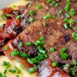 Close up fried lambs liver and port onions on polenta with chives.