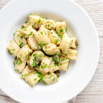 Overhead ricotta cheese gnocchi with caper butter sauce.