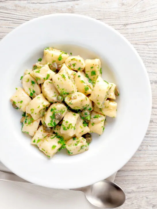 Overhead ricotta cheese gnocchi with caper butter sauce.