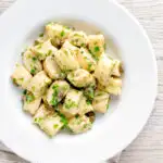 Overhead ricotta cheese gnocchi with caper butter sauce featuring a title overlay.