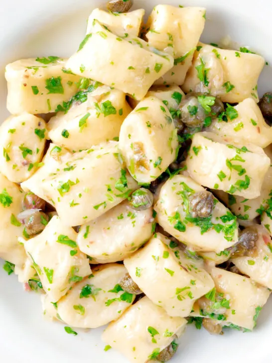 Close up overhead ricotta cheese gnocchi with caper butter sauce.