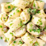 Close up overhead ricotta cheese gnocchi with caper butter sauce featuring a title overlay.