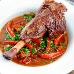 Slow cooker braised lamb shanks in a red wine, tomato, garlic and pepper sauce.