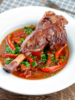 Slow cooker braised lamb shanks in a red wine, tomato, garlic and pepper sauce.