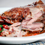 Detail of cooked meat from slow cooked lamb shanks in red wine sauce.