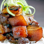 Close up sticky twice cooked pork belly with pineapple and soy sauce featuring title overlay.