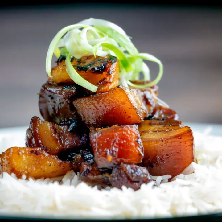 Twice cooked sticky pork belly with pineapple and soy sauce served with rice and spring onions.