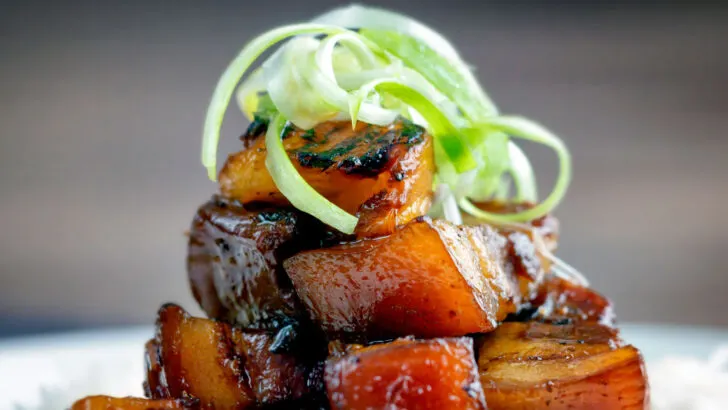 Twice cooked sticky pork belly with pineapple and soy sauce served with rice and spring onions.