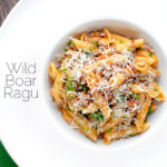 Overhead wild boar ragu or cinghiale al ragu with grated parmesan cheese featuring a title overlay.