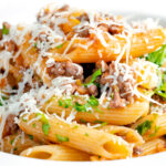 Close up wild boar ragu or cinghiale al ragu with grated parmesan cheese.