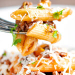 Close up wild boar ragu or cinghiale al ragu with penne pasta on a fork.