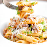 Wild boar ragu or cinghiale al ragu with penne pasta on a fork.