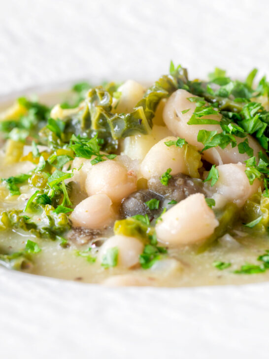 Close-up vegan cabbage and cannellini bean soup with potatoes and capers.