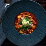 Overhead corned beef stew with baked beans and potatoes.