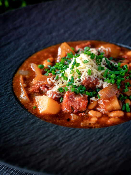 Close-up corned beef stew with baked beans and potatoes.