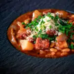 Close-up corned beef stew with baked beans and potatoes featuring a title overlay.