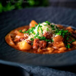 Corned beef stew with baked beans and potatoes featuring a title overlay.